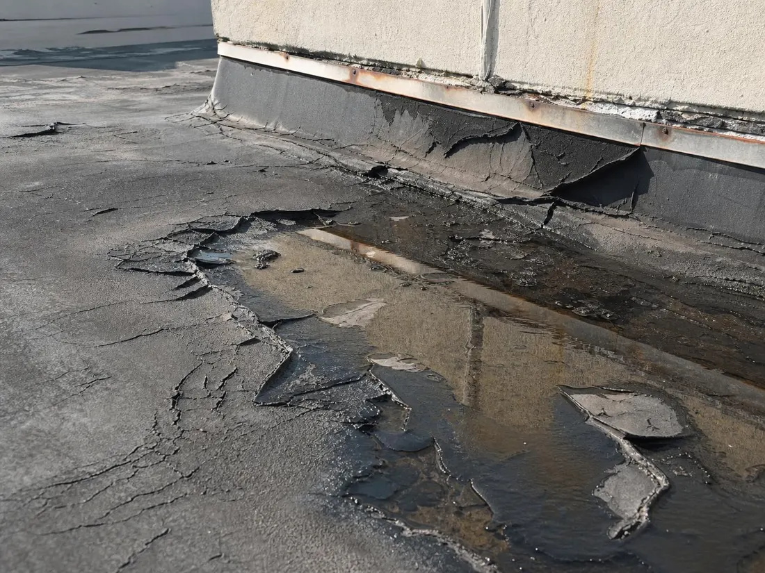 Cracked seams, ponding water and rusted parapet flashing on an aging commercial roof