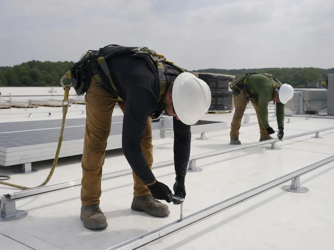 Commercial solar crew bolting racking rails to a flat TPO roof