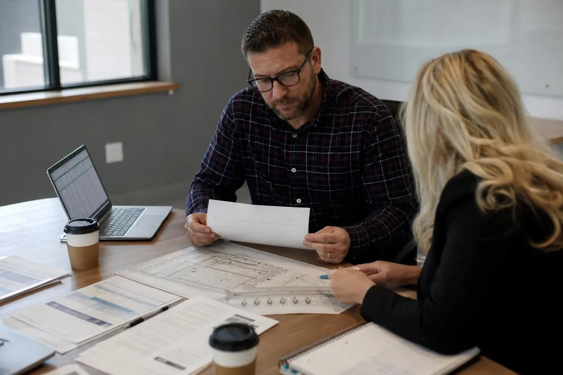 Business owner and consultant reviewing California EV charging rebate paperwork and a site plan